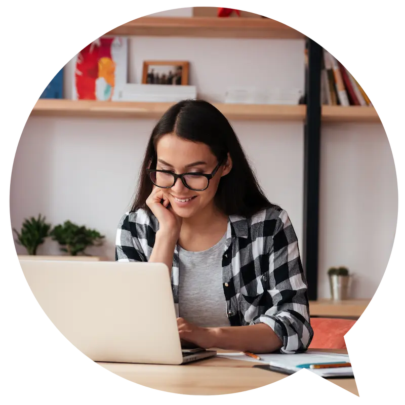 Young woman with glasses at a desk using her laptop